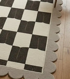 Checkered rug with scalloped edge on a wooden floor