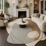 A large abstract area rug in beige, cream, and light blue-gray tones with thin brown line details, styled in a modern living room with a curved cream sofa, matching armchairs, a round white coffee table, and a fireplace in the background.