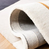 Close-up of a handwoven New Zealand wool rug with a white and beige design on wooden floor