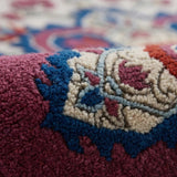 Close-up of a patterned rug with intricate designs in red, blue, and beige.