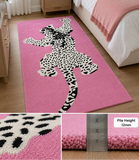 A pink rectangular area rug with a large black-and-white spotted animal silhouette design, shown in a bedroom setting. Two inset detail panels at the bottom show the plush pile texture and pile height of 12 mm.