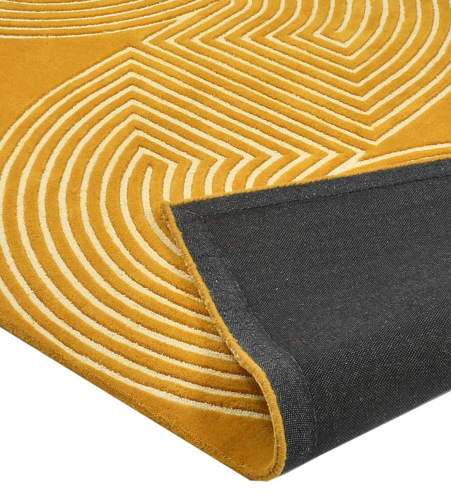 A close-up of a yellow rug with a cream geometric wavy pattern and a folded dark gray underside showing the backing.